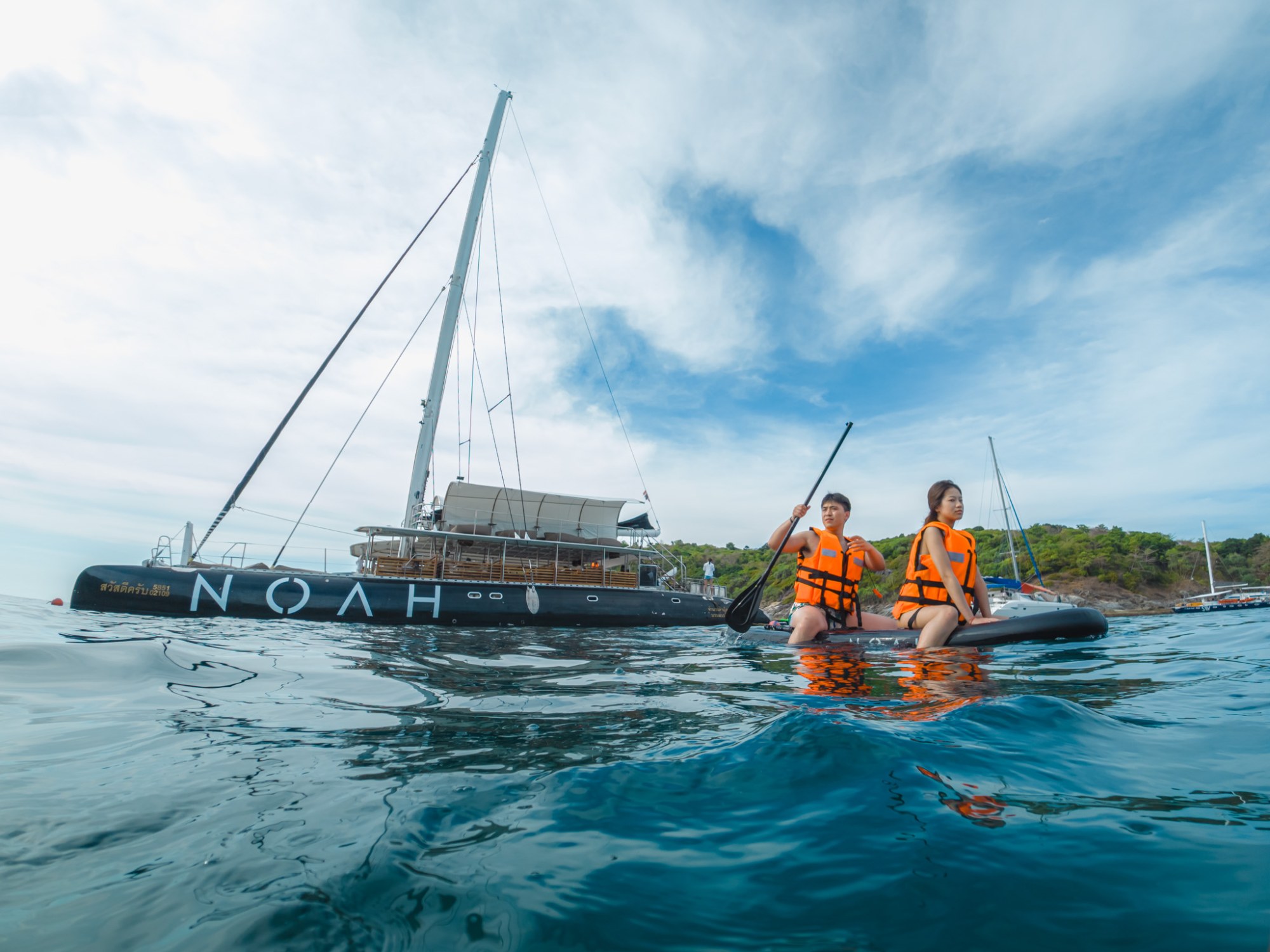 Paddleboarding beside Noah Catamaran at Racha Island